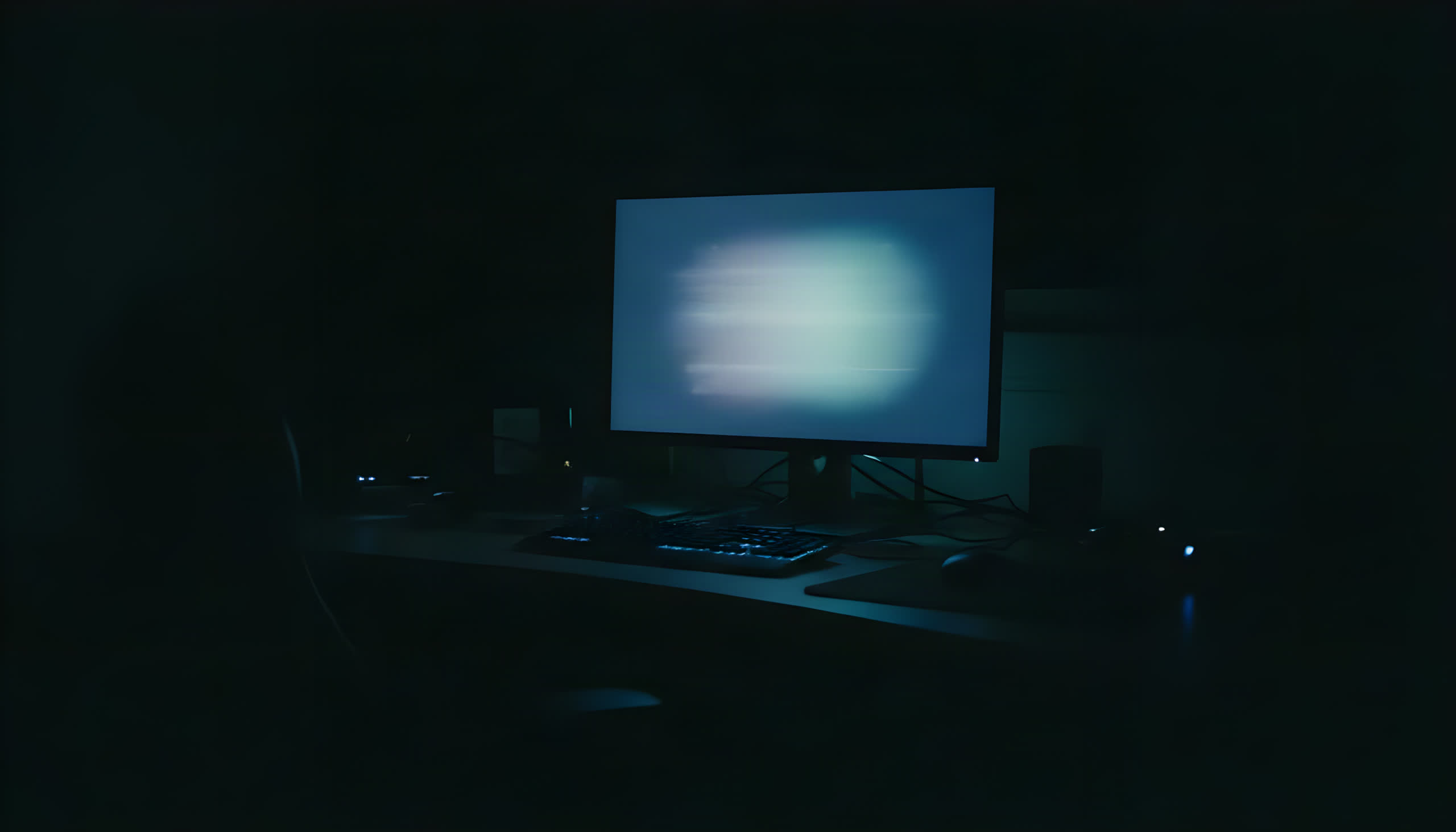 Editing desk in a dark room, lit only by the glow of a monitor