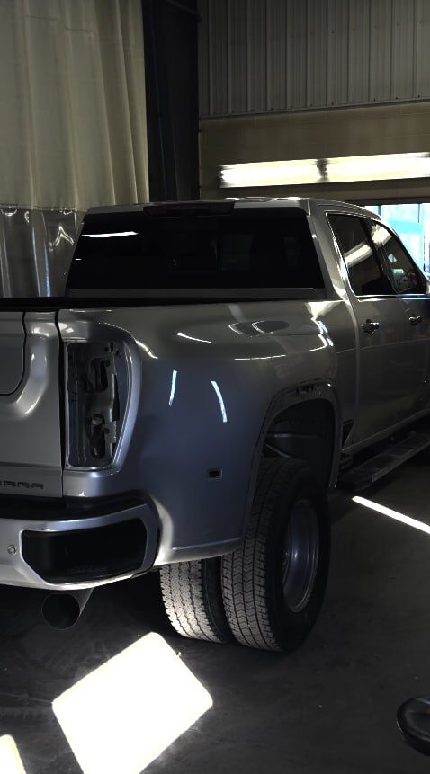 Silver GMC Sierra dually pickup in the bay with its rear tail light removed mid-repair