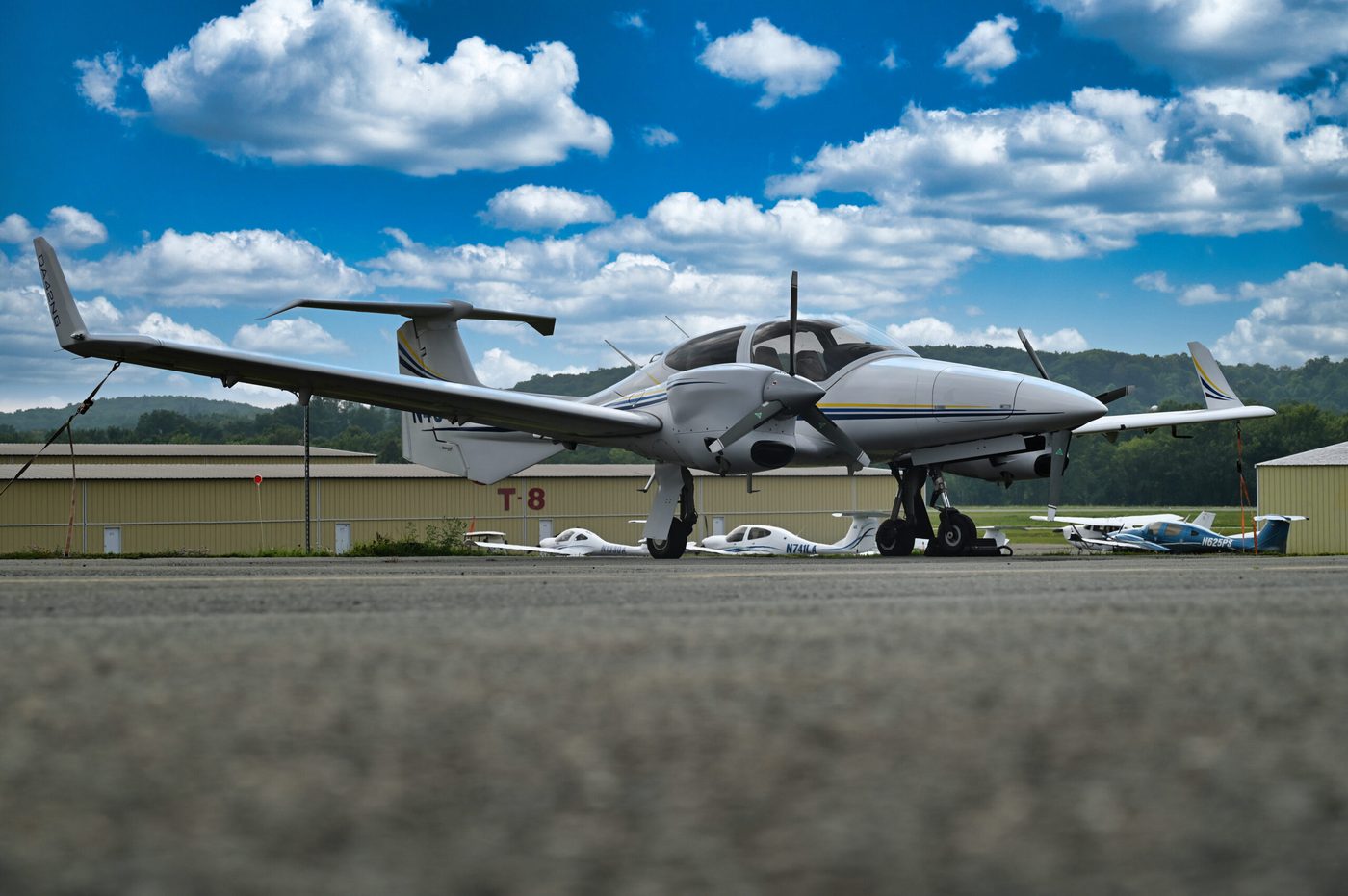 Twin-engine aircraft waiting on the ramp under scattered cumulus